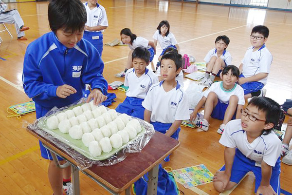 有機米おにぎりを試食する小学生たちの画像